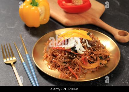 Japchae coreano, Stir Fried Glass Noodles, manzo e verdure, serviti su piatto d'oro. Cibo popolare per Seollal Foto Stock