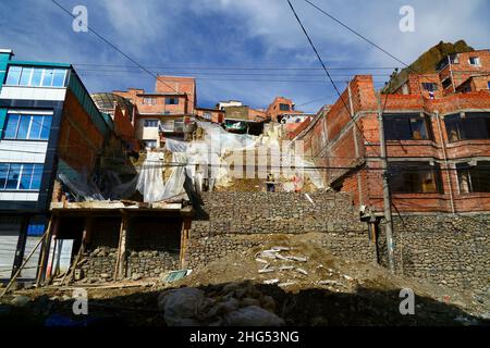 La Paz, Bolivia: Lavoratori municipali che stabilizzano una collina e case danneggiate con gabbie piene di rocce/bungalow in un sito nel distretto di Tembladerani/Cotahuma. Scavi non autorizzati e movimento terra da parte di uno dei proprietari hanno causato il crollo di parte della collina. Molti dei quartieri collinari di la Paz sono stati costruiti in aree instabili senza permessi adeguati o controlli sugli edifici. Il cedimento e l'erosione che causano frane e case crollate sono comuni, soprattutto nella stagione delle piogge. In questo incidente 2 case hanno dovuto essere demolite e altre 6 sono state gravemente colpite. Foto Stock