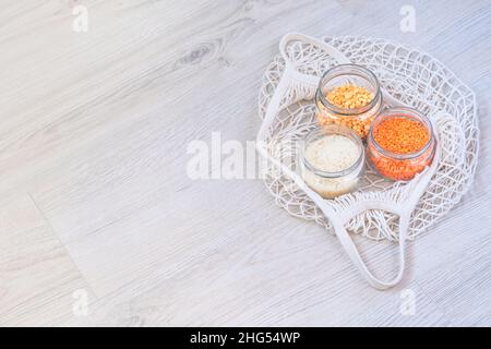 Cereali e cereali in un negozio di rifiuti zero. Prodotti biologici in cucina. Lenticchie, piselli e riso in vasetti di vetro su sfondo di legno. Shopping ecologico Foto Stock