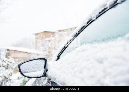 Auto coperte di neve fresca bianca, specchio laterale per auto ravvicinata, cielo invernale Foto Stock