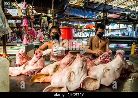 Bangkok, Tailandia. 18th Jan 2022. I lavoratori preparano teste di maiale prima che siano venduti nel mercato. I lavoratori al mercato all'ingrosso noi di Bangkok preparano carni di maiale appena macellate per la vendita il 18 gennaio 2022. A causa di una carenza di offerta, di speculazioni di mercato e di una potenziale epidemia di peste suina africana, il costo della carne suina in Thailandia è alle stelle, causando un aumento vertiginoso del prezzo dei prodotti alimentari di base. La rapida inflazione ha portato a un improvviso aumento a livello nazionale di tutto, dai prodotti alimentari di strada ai supermercati. Credit: SOPA Images Limited/Alamy Live News Foto Stock