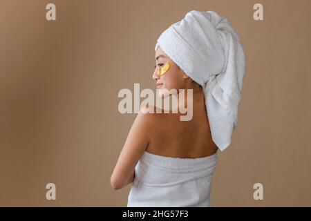 Giovane donna con cerotto dorato sotto l'occhio in piedi in studio Foto Stock