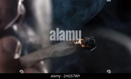 Dita che tengono il giunto marijuana. Fumo di sigaretta di cannabis. Foto Stock