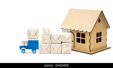 Carrello blu in miniatura che consegna pacchi di materiale in una casa modello isolata su sfondo bianco. Spostarsi in una nuova casa. Foto Stock
