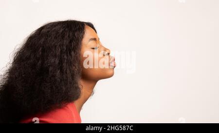 Profile Shot of Young Black Woman Poarting Lips over White Studio background Foto Stock