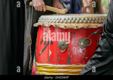 Palcoscenico che colpisce un tamburo giapponese rosso (taiko) Foto Stock