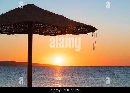 Bella spiaggia e oceano alba in vimini intrecciato canna ombrello al mattino Foto Stock