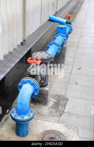 Valvola dell'acqua vicino al muro di cemento, tubi dell'acqua Uniti con il sistema di valvole di alimentazione dell'acqua sulla strada. Foto Stock