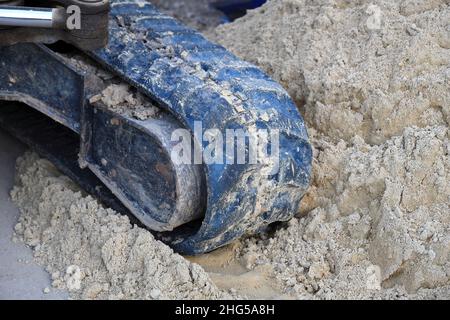 Primo piano apripista caterpillar usato e sporco in gomma. Primo piano del nastro cingolato dell'escavatore in cantiere Foto Stock