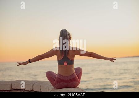 Donna meditante, seduta in posizione lotus al mare Foto Stock