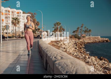 Atletica sportiva signora che corre attivamente sul lungomare Foto Stock