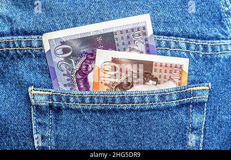 Le banconote britanniche sporgono dalla tasca blu dei jeans in primo piano Foto Stock