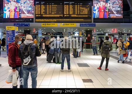 Napoli, Italia - 24 dicembre 2021: Nella stazione centrale, i passeggeri in attesa consultare gli orari di arrivo e partenza dei treni, guardando Foto Stock