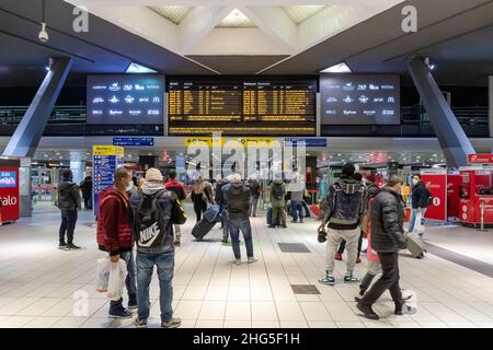 Napoli, Italia - 24 dicembre 2021: Nella stazione centrale, i passeggeri in attesa consultare gli orari di arrivo e partenza dei treni, guardando Foto Stock