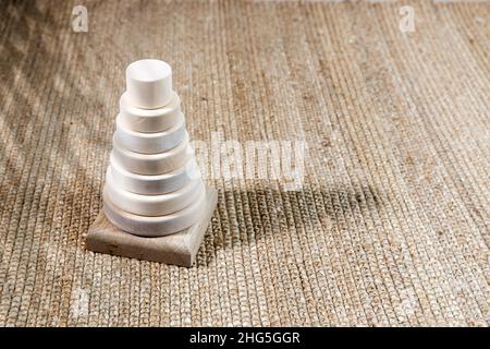 Piramide di legno su un tappeto di vimini, ombra da una palma. Spazio vuoto per il testo. Foto Stock