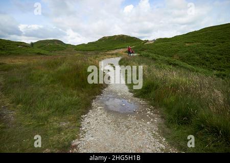 uomo e giovane ragazza escursionisti a piedi il percorso intorno loughrigg cadde lago distretto, cumbria, inghilterra, regno unito Foto Stock