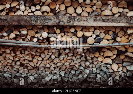 Legno naturale segato tronchi come sfondo. Tronchi da muro impilati. Accatastato di legna da ardere disposto con spaccature su sezione trasversale. Sfondo astratto testurizzato. Foto Stock