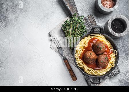 Pasta di pomodoro vegana con polpette a base vegetale in padella. Sfondo bianco. Vista dall'alto. Spazio di copia Foto Stock