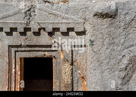Lucertola blu che si crogiola al sole seduto sul muro dell'antica tomba di pietra a Myra Foto Stock