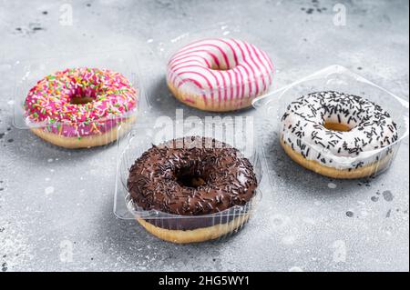 Ciambelle smaltate assortite su un tavolo da cucina. Sfondo grigio. Vista dall'alto Foto Stock