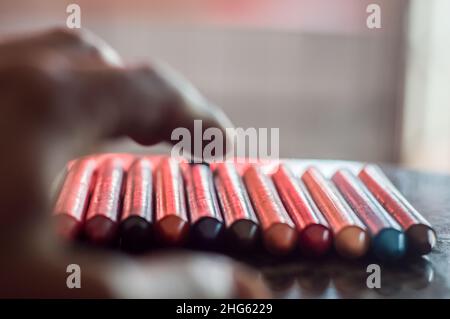 La diversità di colore del pastello focalizzata e la mano che raccoglie un pastello marrone, spazio di copia Foto Stock