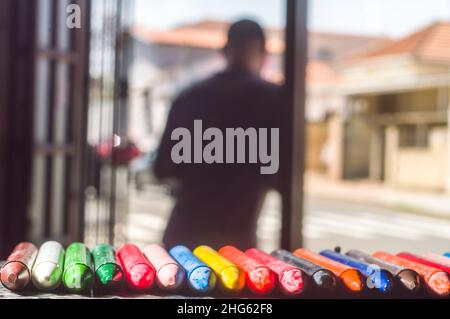 La diversità di colore del pastello focalizzata e la mano che raccoglie un pastello marrone, spazio di copia Foto Stock