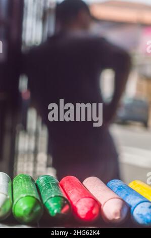 La diversità di colore del pastello focalizzata e la mano che raccoglie un pastello marrone, spazio di copia Foto Stock