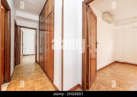 Corridoio con porte e armadi in mogano in una casa residenziale con pavimento in parquet chiaro Foto Stock
