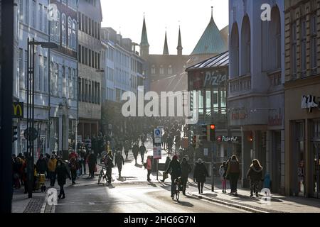 Lubeck, Germania, 15 gennaio 2022: Folla di persone in controluce camminando lungo la strada dello shopping nel centro della città storica città vecchia, selecte Foto Stock