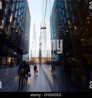 I pulitori per finestre con attrezzatura da arrampicata si riflettono nelle finestre degli edifici moderni con il grattacielo Shard dietro, Londra. Foto Stock