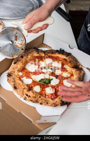 Pizzaiolo affettare la torta Margherita appena sfornata Foto Stock