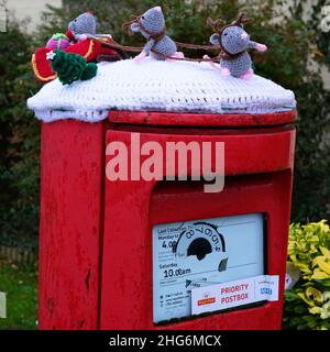 Gennaio 2022 - topi di lana a maglia come Santa e renna e slitta in cima a una casella postale nel villaggio di Mark, Somerset, Inghilterra, Regno Unito Foto Stock