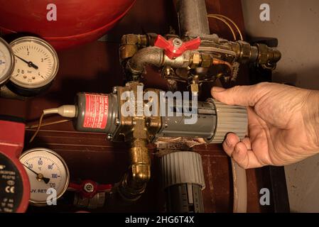 Una mano gira la manopola del comando su un sistema di teleriscaldamento, Danimarca, 18 gennaio 2022 Foto Stock