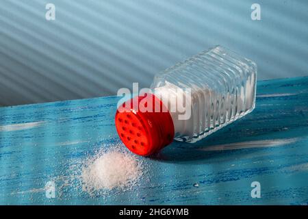 scuotitore del sale capovolto con sale sul lato che rappresenta il consumo eccessivo Foto Stock