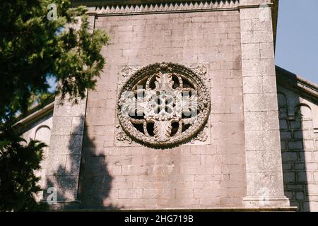 Rosone sulla facciata in pietra di una vecchia chiesa Foto Stock