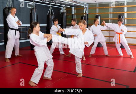 Ragazzi che lavorano in coppia, padroneggiare i calci in classe karate Foto Stock