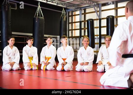 Bambini con il loro istruttore maschio che si pone in classe karate Foto Stock