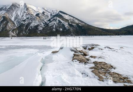 Pattinaggio ed escursioni sul lago Minnewanka ghiacciato nel Parco Nazionale di Banff, Alberta, Canada Foto Stock