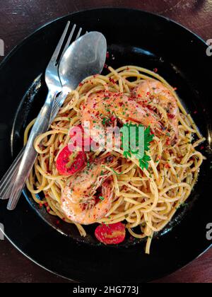 Delizioso pesce aglio olio con gamberi grandi su un piatto nero. Vista dall'alto Foto Stock
