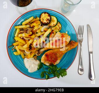Piatto con cosce di pollo al forno e zucchine Foto Stock