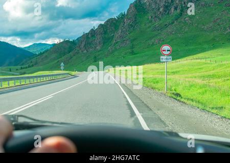 vista del segnale stradale che vieta il sorpasso dall'interno della vettura, dal lato conducente su un'autostrada asfaltata suburbana Foto Stock