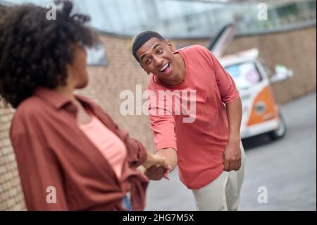 Uomo che si piega su mano di mano di camminare donna Foto Stock