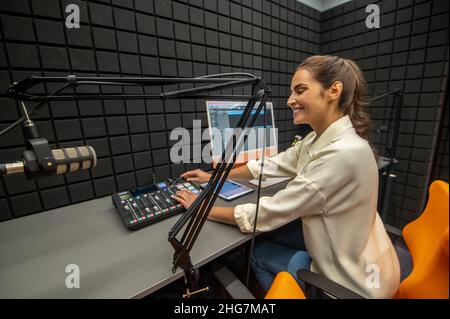 Gioioso tecnico del suono che regola il livello del volume su un mixer audio Foto Stock