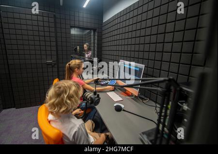 I bambini si siedono alla scrivania durante la registrazione del suono Foto Stock