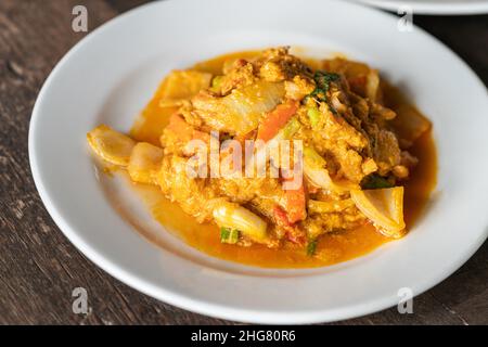 Primo piano su crabmeat fritto con curry in polvere e uova, frutti di mare sani cibo tailandese su tavola di legno, luce naturale. Foto Stock