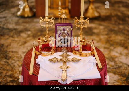 Croce, corone d'oro e candelieri si trovano sul tavolo della chiesa Foto Stock