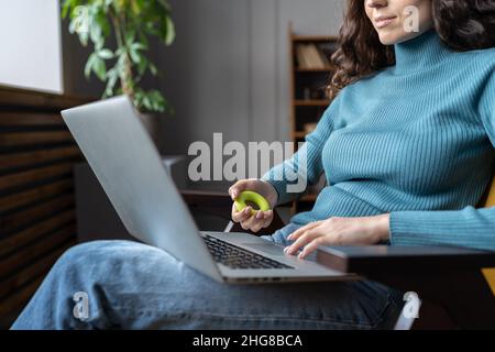 Dipendente femminile che si esercita con espansore mano mentre lavora su un computer portatile in ufficio Foto Stock
