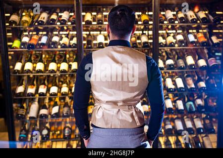 buon produttore di vino maschile di successo sta degustando un sapore e controllando la qualità del vino rosso Foto Stock