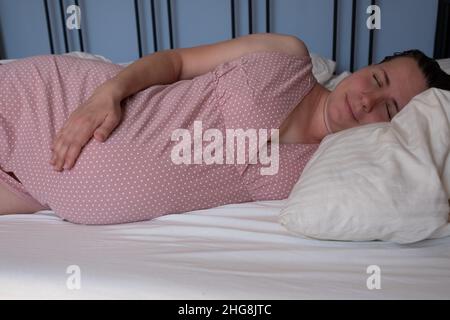 Donna incinta dorme tranquillamente in camera da letto Foto Stock