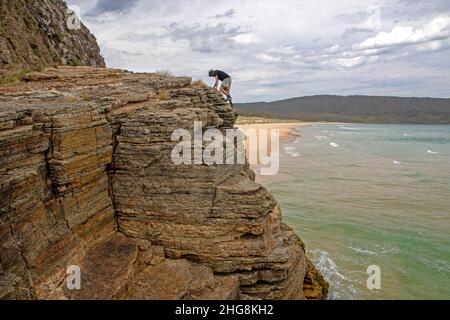 Uomo che si arrampica sulle scogliere della Baia di Moorina Foto Stock